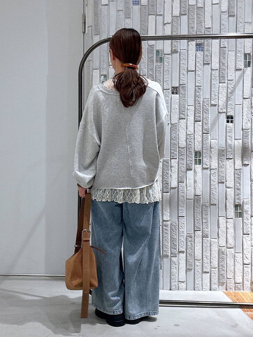 ブラウン系のショルダーバッグ、ブルー系のデニムパンツ、ブラック系のその他シューズを着用したレディースの春コーディネートの4枚目の写真