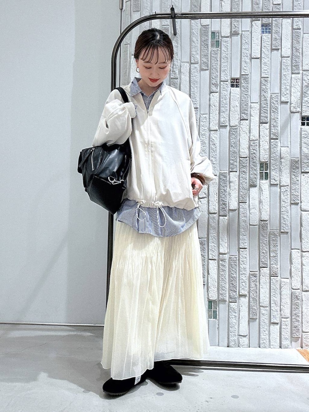 ブラック系のショルダーバッグ、ブルー系のシャツ/ブラウス、ホワイト系のブルゾンを着用したレディースの春コーディネートの3枚目の写真