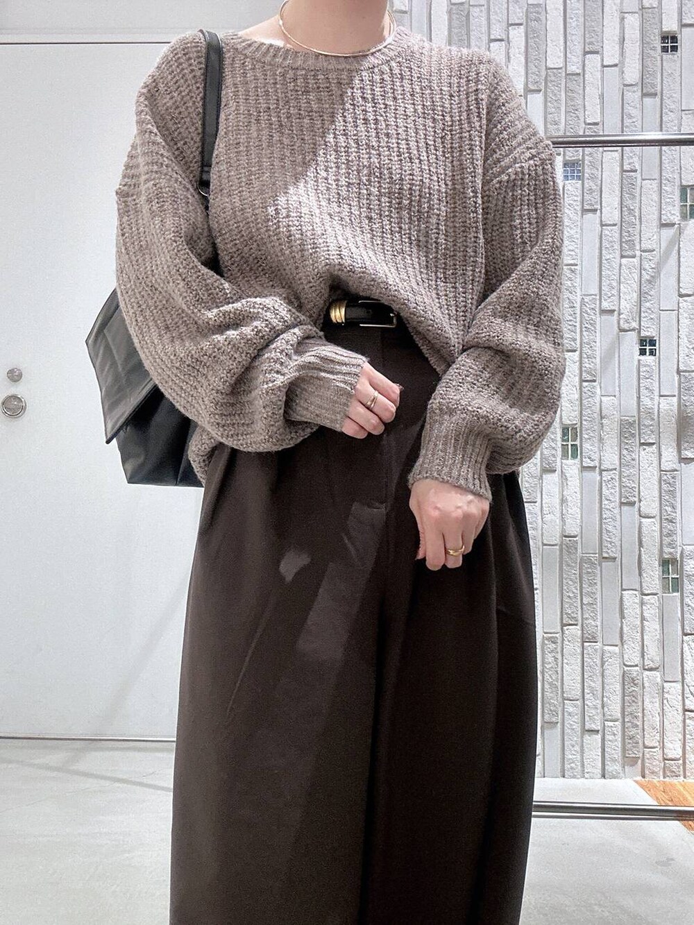 ブラウン系のスラックス、ブラック系のブーツ、ブラウン系のニット/セーターを着用したレディースの冬コーディネートの4枚目の写真