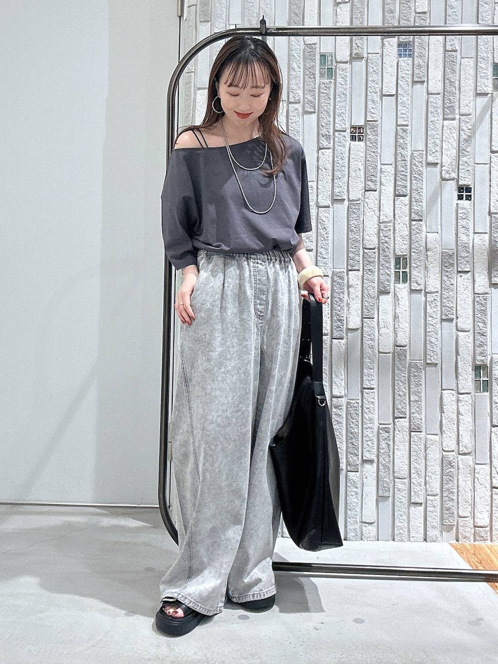 グレー系のTシャツ/カットソー、グレー系のデニムパンツ、ブラック系のサンダルを着用したレディースの春コーディネートの2枚目の写真