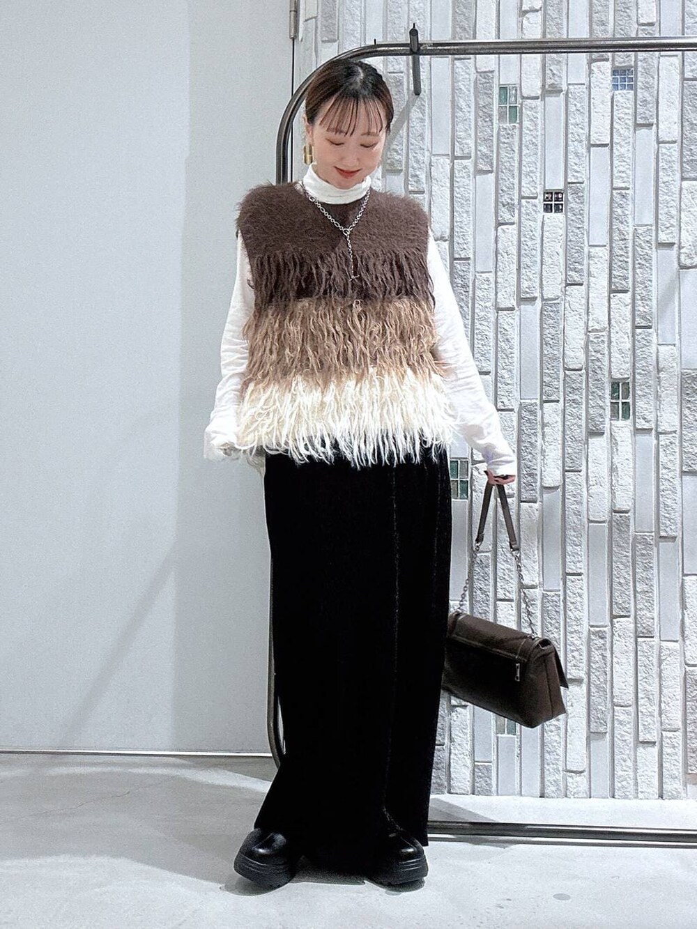 ホワイト系のTシャツ/カットソー、ブラック系のブーツ、ブラック系のスカートを着用したレディースの冬コーディネートの3枚目の写真