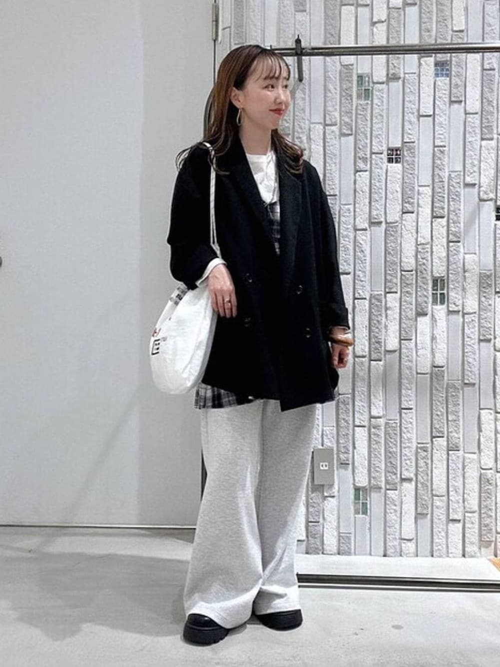 ホワイト系のTシャツ/カットソー、グレー系のスウェットパンツ、ブラック系のその他シューズを着用したレディースの春コーディネートの2枚目の写真