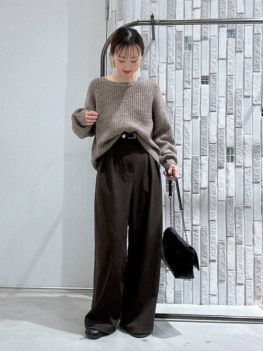 ブラウン系のスラックス、ブラック系のブーツ、ブラウン系のニット/セーターを着用したレディースの冬コーディネートの2枚目の写真