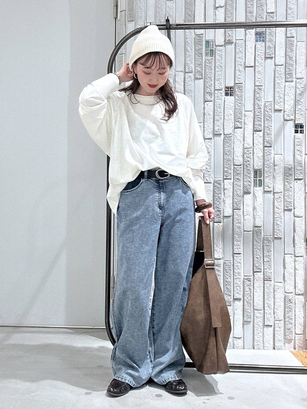 ブルー系のデニムパンツ、ブラウン系のショルダーバッグ、ホワイト系のTシャツ/カットソーを着用したレディースの春コーディネートの2枚目の写真