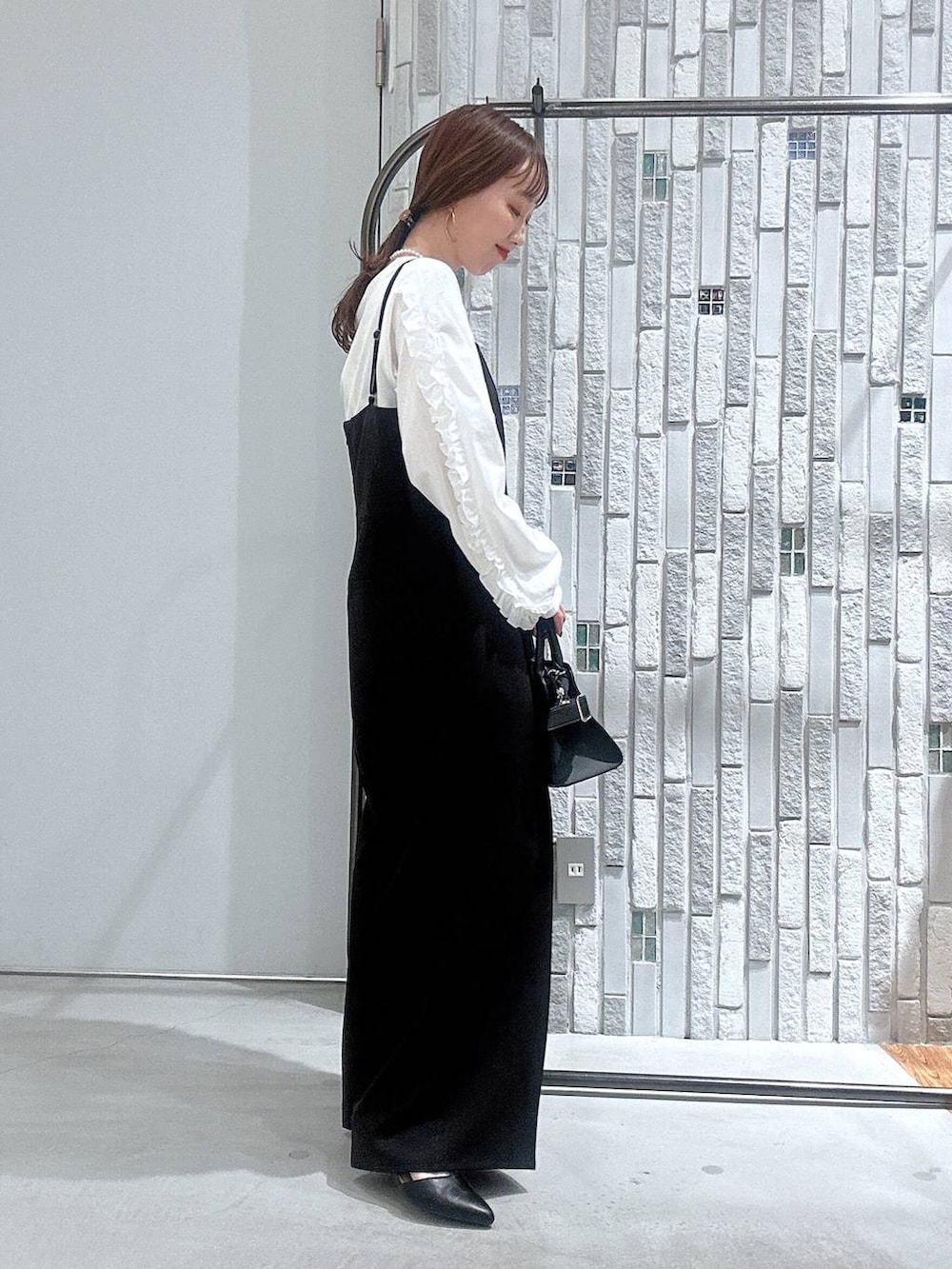 ブラック系のサロペット/オーバーオール、ホワイト系のTシャツ/カットソー、ブラック系のショルダーバッグを着用したレディースの冬コーディネートの6枚目の写真