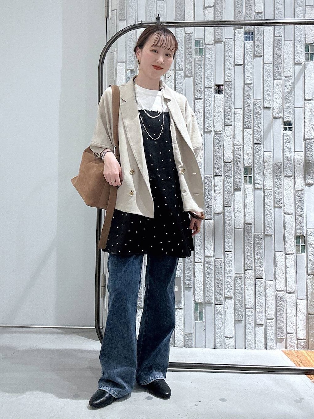 ブラウン系のショルダーバッグ、ブルー系のデニムパンツ、ベージュ系のテーラードジャケットを着用したレディースの春コーディネートの2枚目の写真