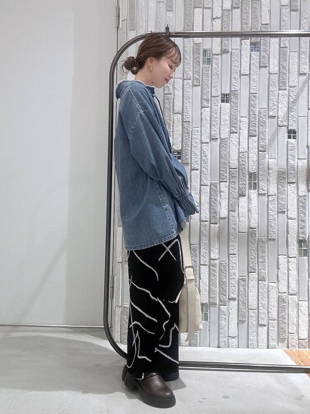 ホワイト系のショルダーバッグ、ブラウン系のサンダル、ブラック系のスカートを着用したレディースの冬コーディネートの3枚目の写真