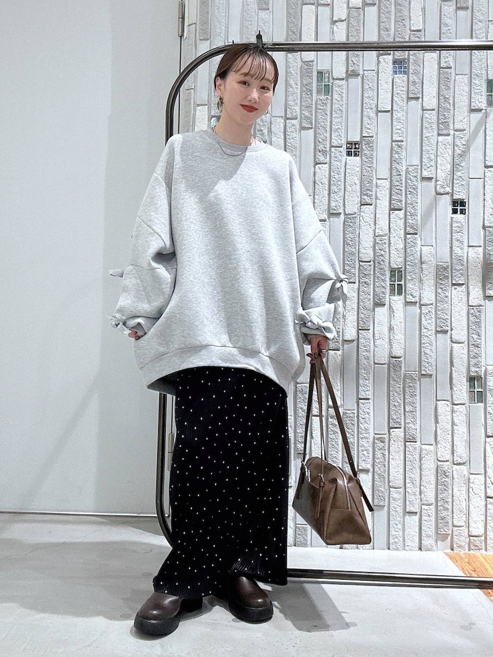 ブラウン系のサンダル、ブラウン系のボストンバッグ、グレー系のスウェットを着用したレディースの冬コーディネートの2枚目の写真