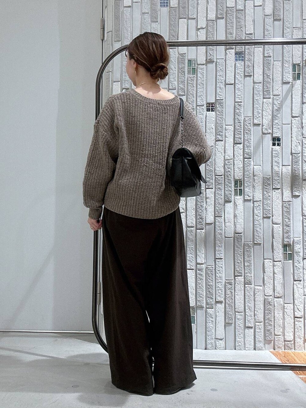 ブラウン系のスラックス、ブラック系のブーツ、ブラウン系のニット/セーターを着用したレディースの冬コーディネートの3枚目の写真