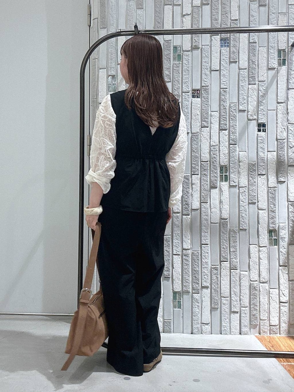 ブラウン系のショルダーバッグ、ホワイト系のTシャツ/カットソー、ブラック系のつなぎ/オールインワンを着用したレディースの春コーディネートの4枚目の写真