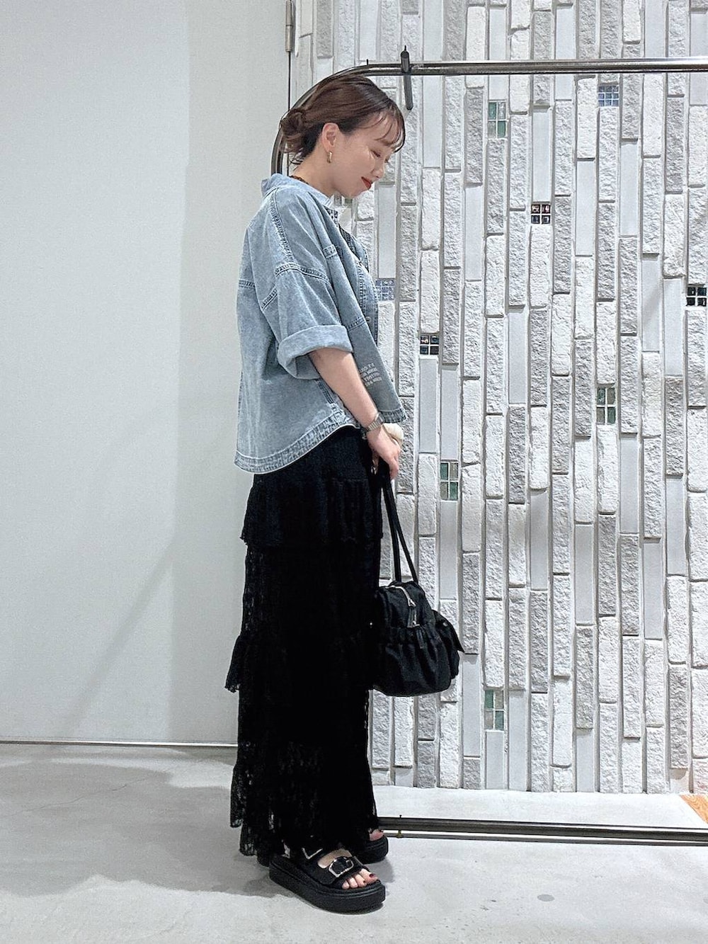 ブラック系のサンダル、ブルー系のシャツ/ブラウス、ブラック系のボストンバッグを着用したレディースの春コーディネートの3枚目の写真
