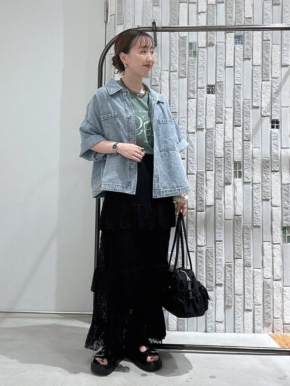 ブラック系のサンダル、ブルー系のシャツ/ブラウス、ブラック系のボストンバッグを着用したレディースの春コーディネートの2枚目の写真