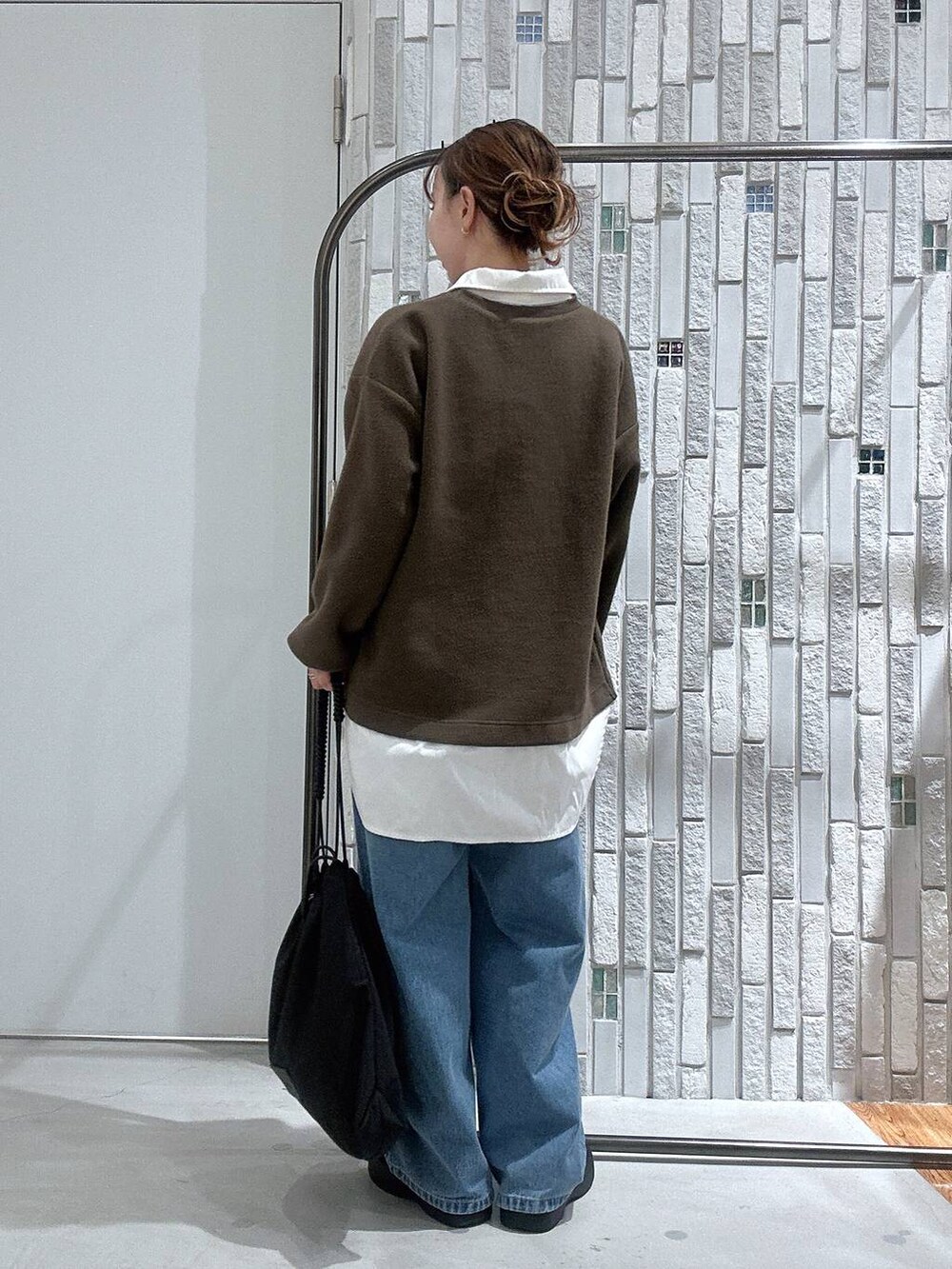 ブラック系のトートバッグ、ブルー系のデニムパンツ、ブラック系のブーツを着用したレディースの冬コーディネートの4枚目の写真