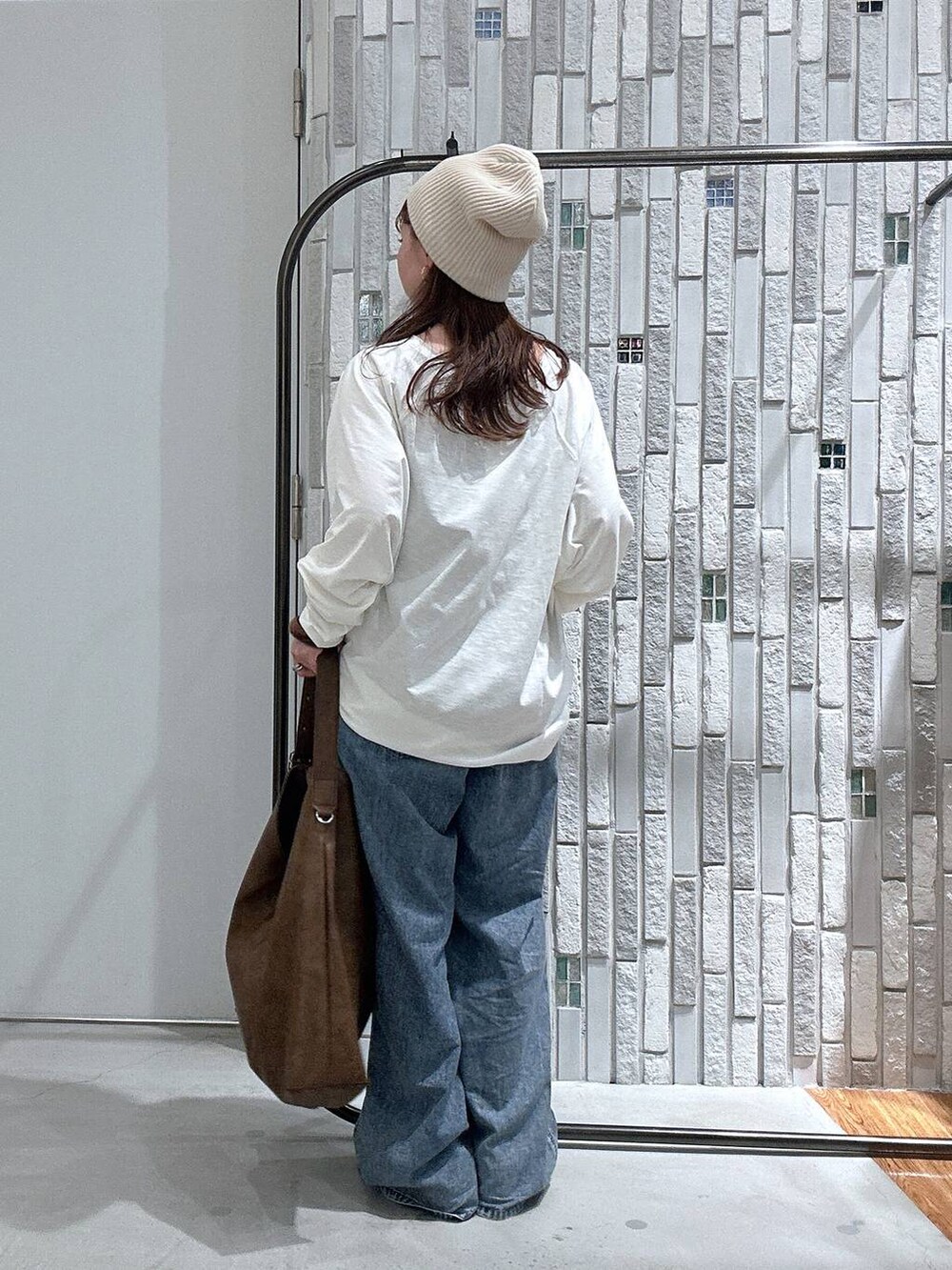 ブルー系のデニムパンツ、ブラウン系のショルダーバッグ、ホワイト系のTシャツ/カットソーを着用したレディースの春コーディネートの3枚目の写真