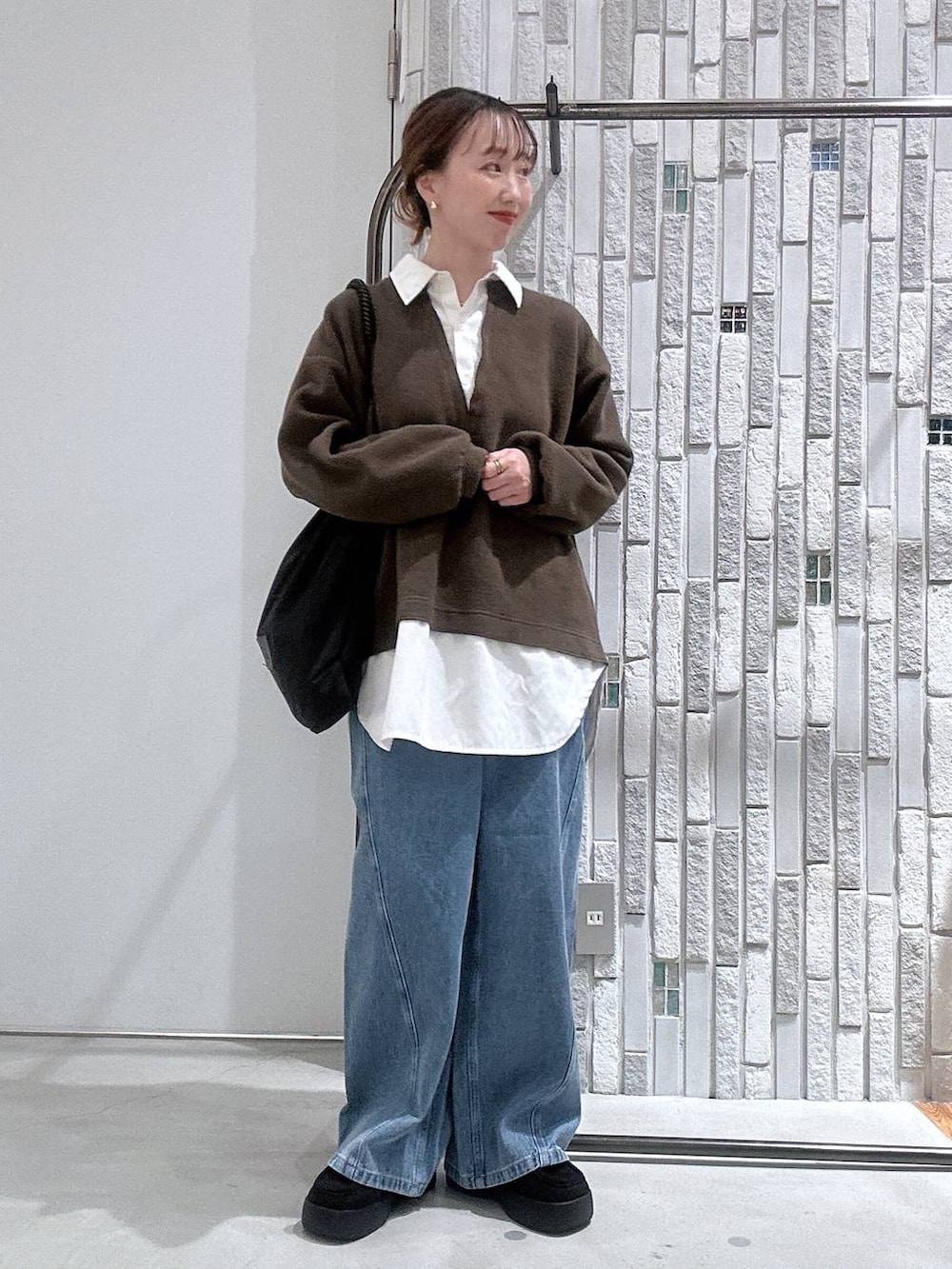 ブラック系のトートバッグ、ブルー系のデニムパンツ、ブラック系のブーツを着用したレディースの冬コーディネートの2枚目の写真