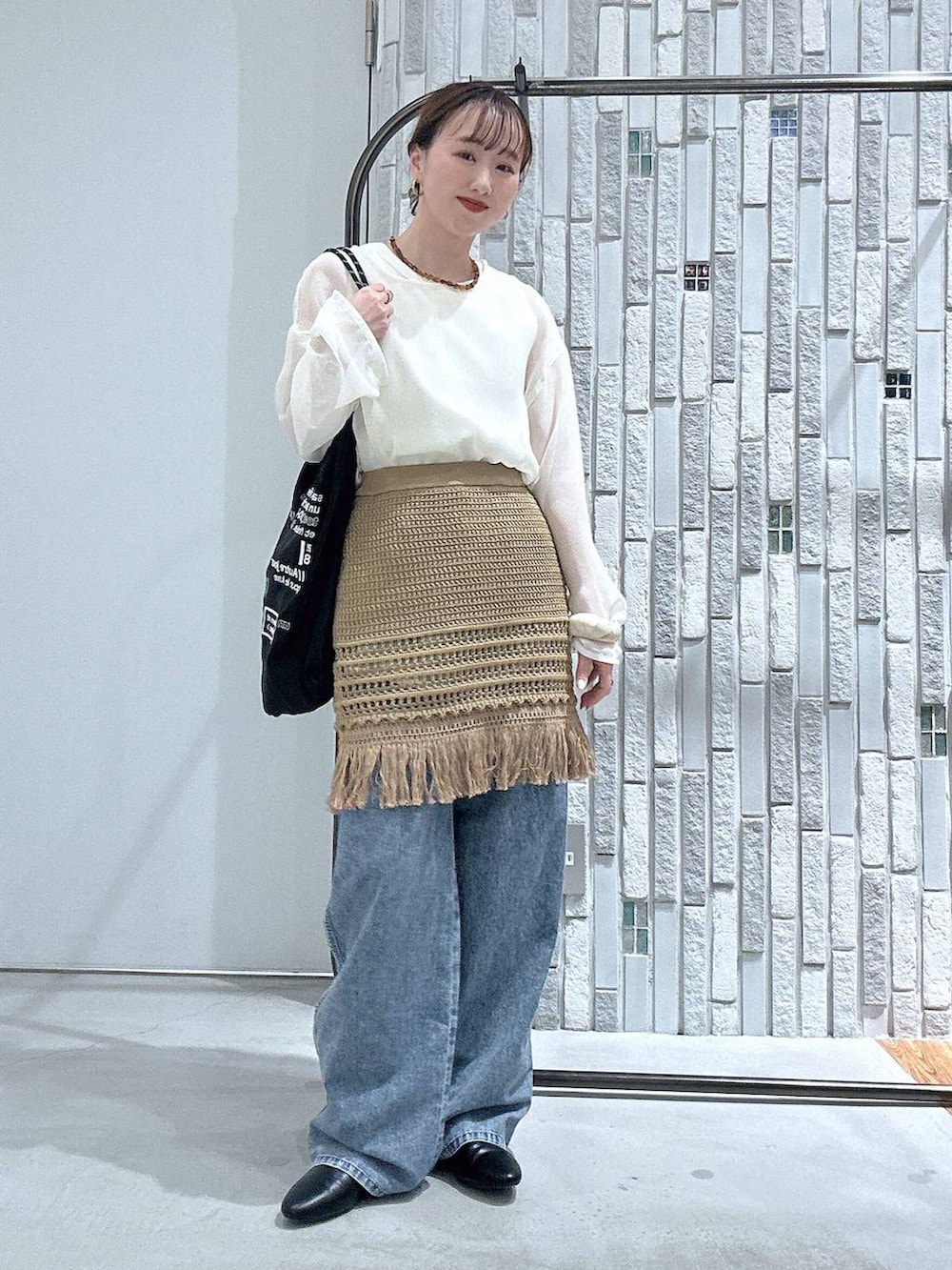 ブルー系のデニムパンツ、ブラック系のトートバッグ、ブラック系のパンプスを着用したレディースの春コーディネートの3枚目の写真