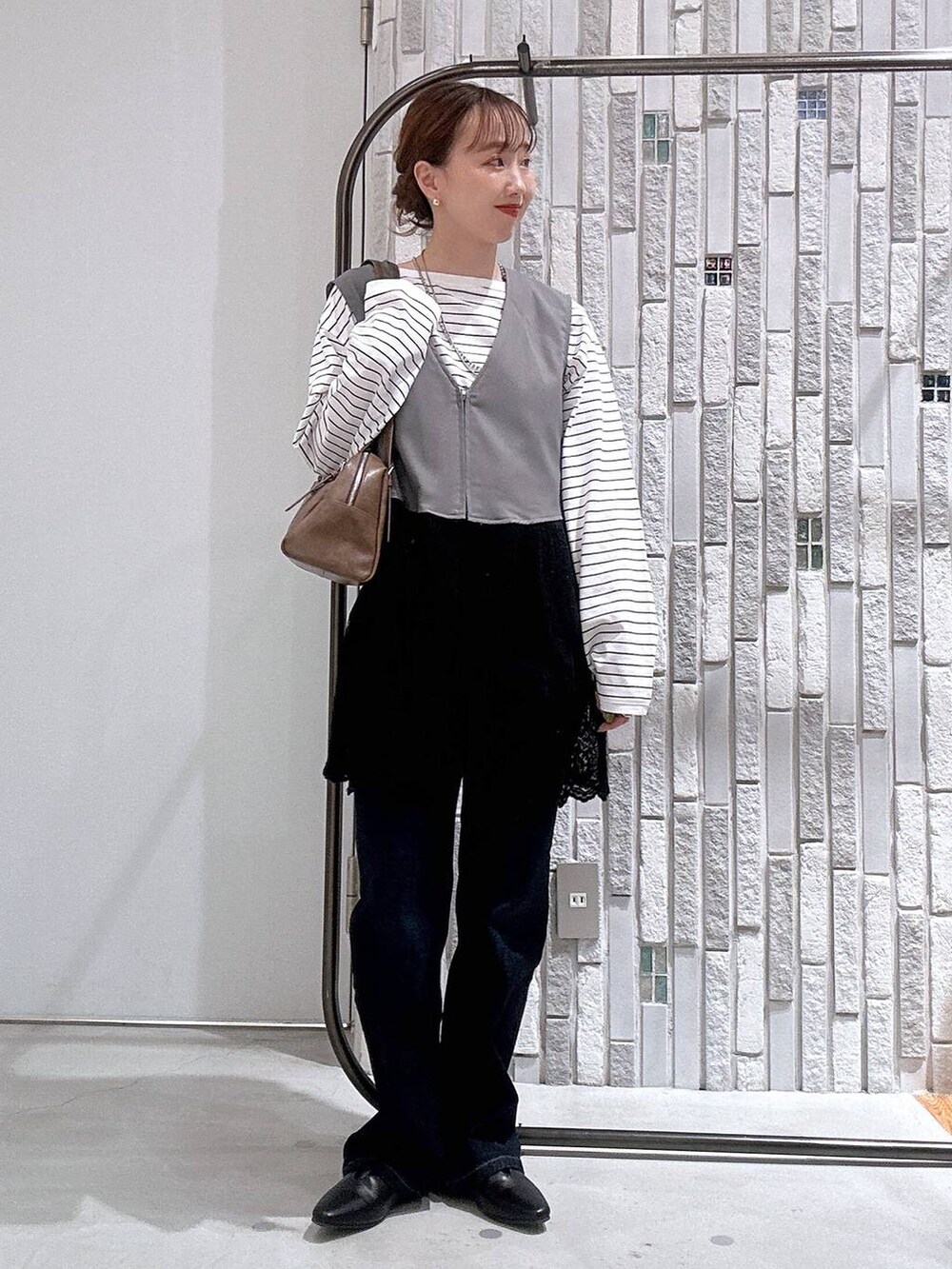 ブラウン系のボストンバッグ、ホワイト系のTシャツ/カットソー、ブルー系のデニムパンツを着用したレディースの冬コーディネートの2枚目の写真