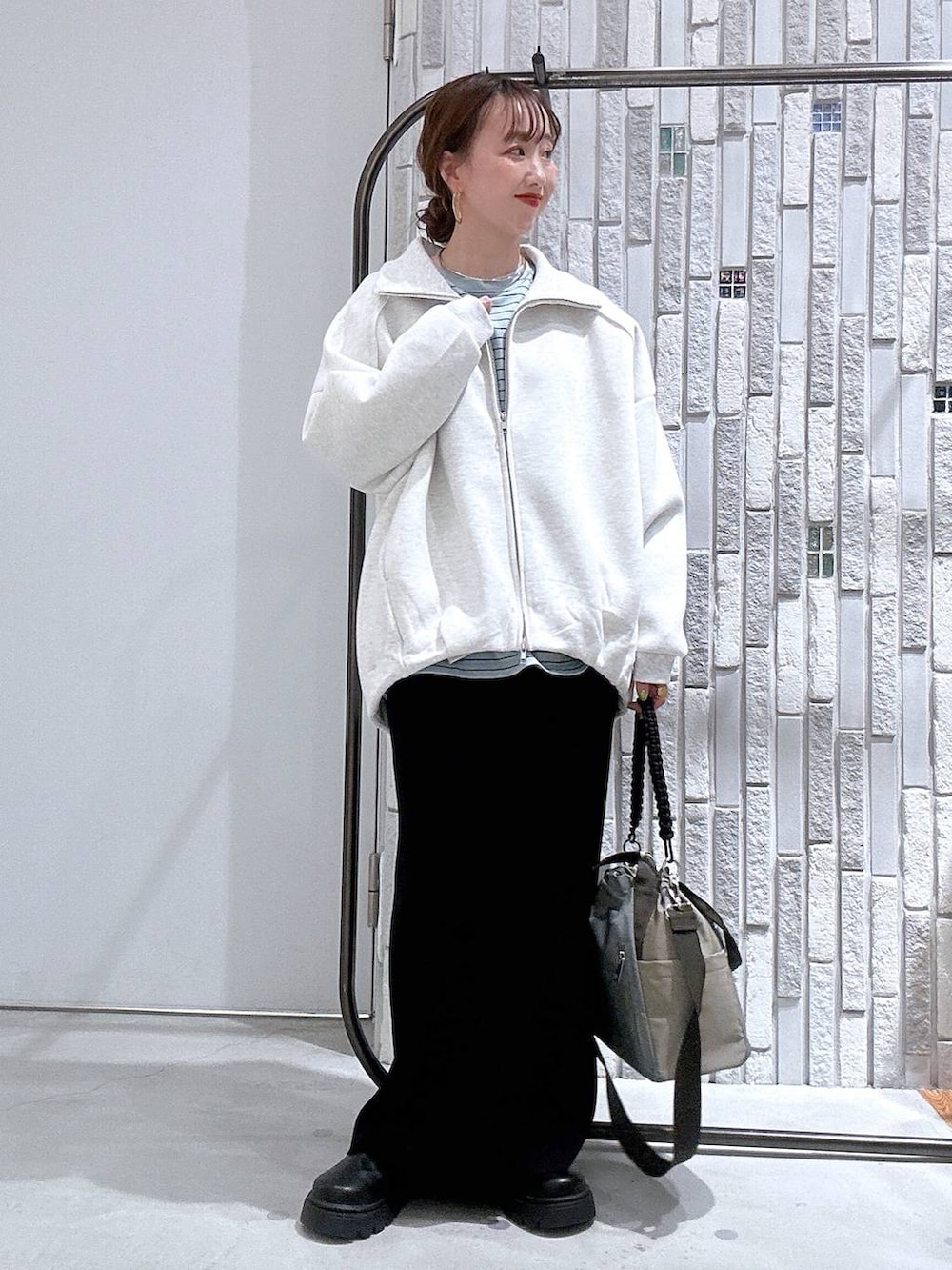 ブラック系のスカート、ブラック系のサンダル、グリーン系のショルダーバッグを着用したレディースの冬コーディネートの2枚目の写真