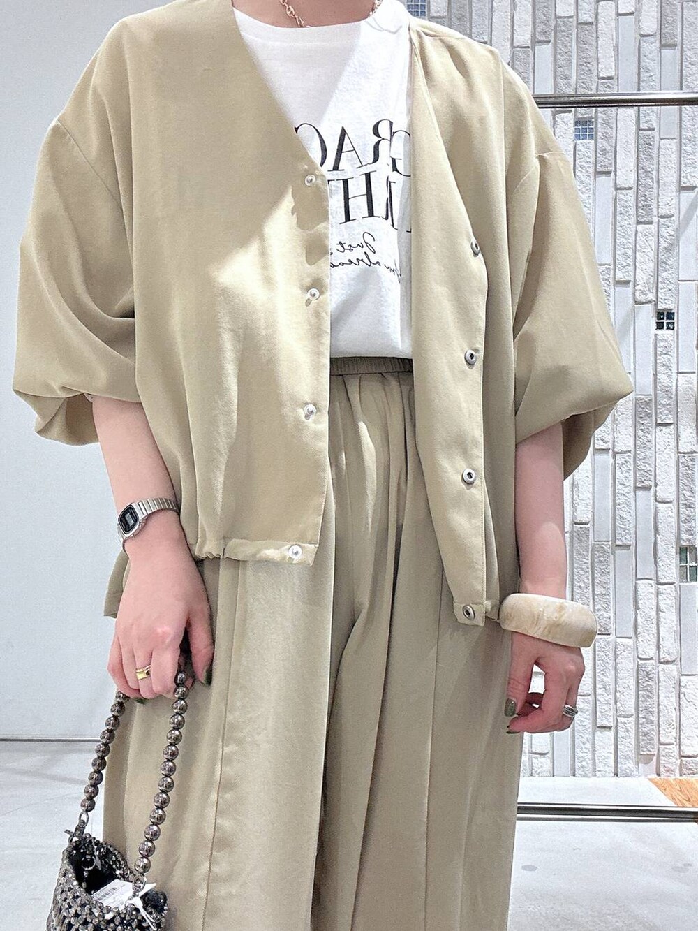 ベージュ系のその他パンツ、ベージュ系のシャツ/ブラウス、シルバー系のショルダーバッグを着用したレディースの春コーディネートの5枚目の写真