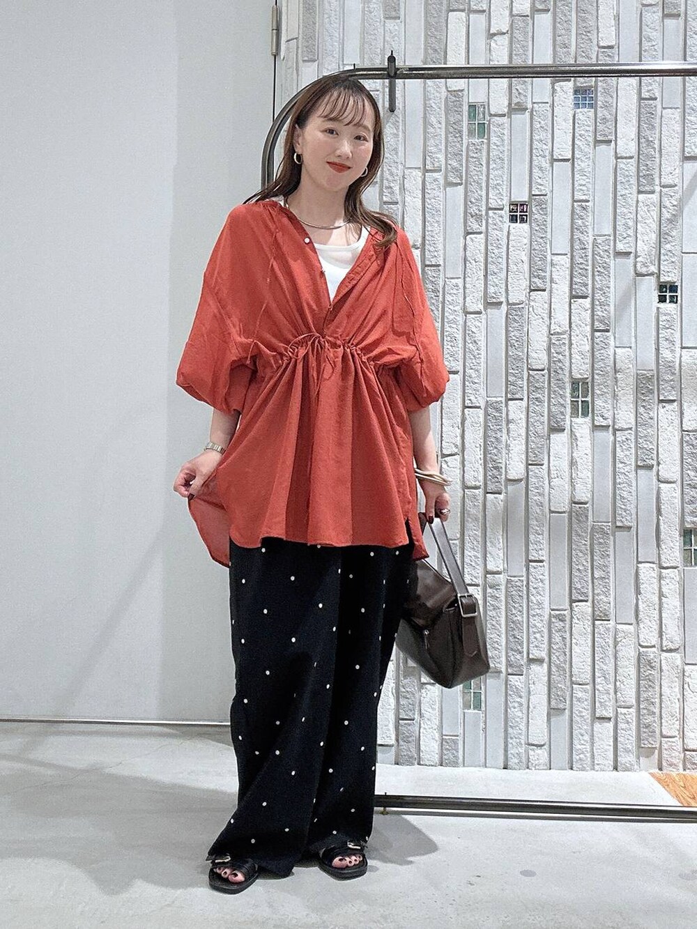 オレンジ系のシャツ/ブラウス、ブラウン系のショルダーバッグ、ブラック系のその他パンツを着用したレディースの夏コーディネートの2枚目の写真