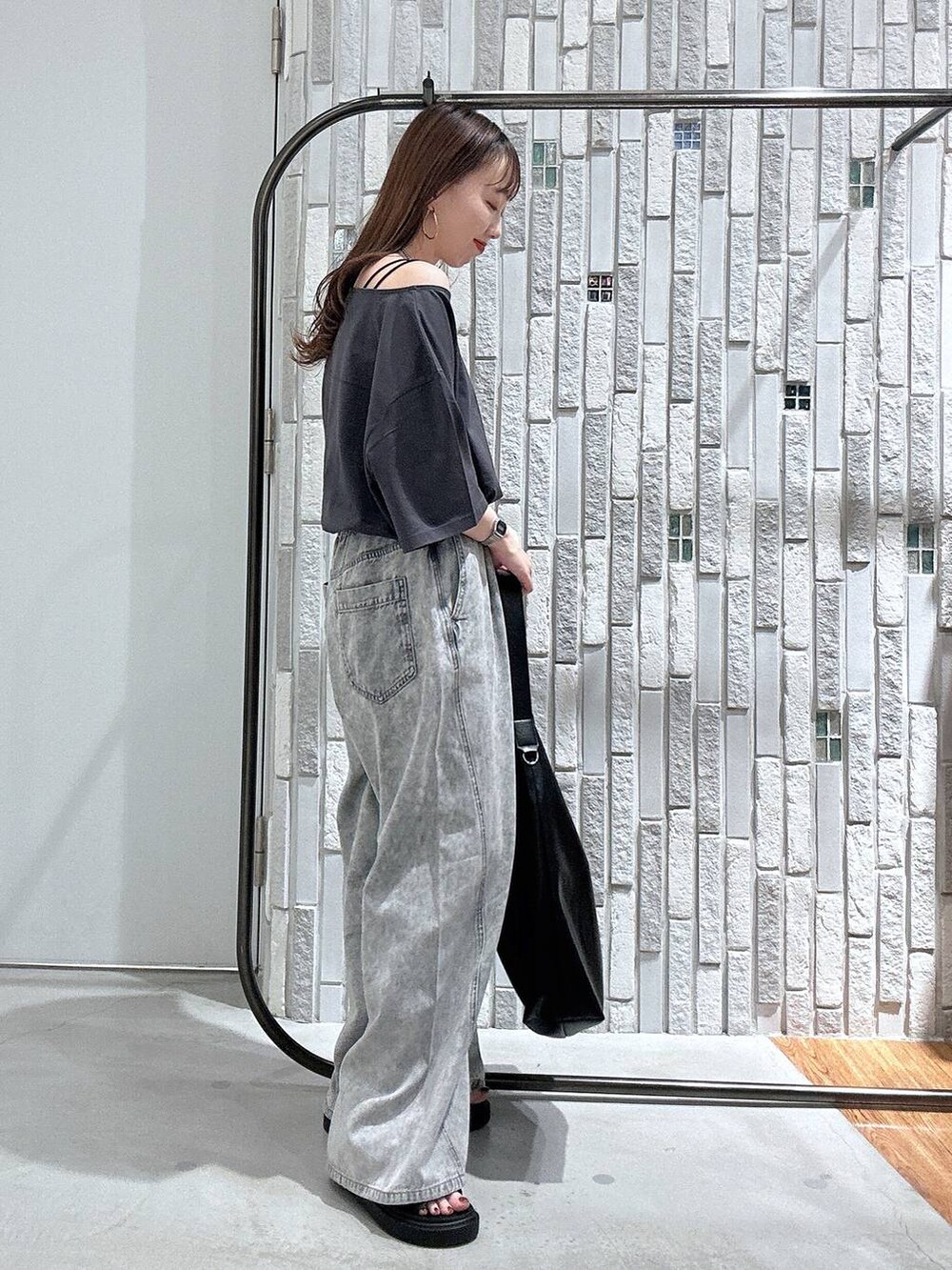 グレー系のTシャツ/カットソー、グレー系のデニムパンツ、ブラック系のサンダルを着用したレディースの春コーディネートの3枚目の写真