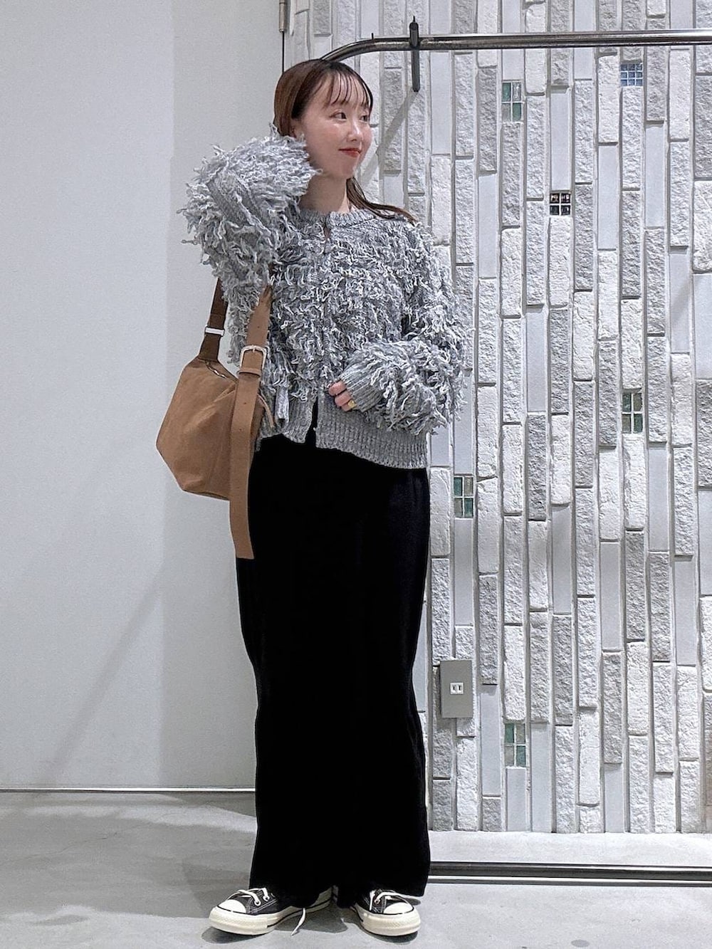 ブラック系のスカート、ブラウン系のショルダーバッグ、ブラウン系のスニーカーを着用したレディースの冬コーディネートの2枚目の写真