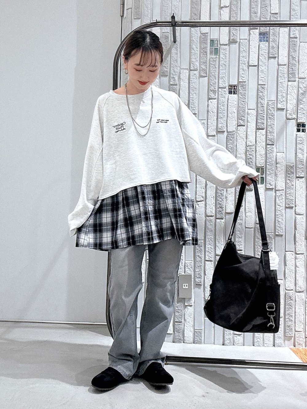 グレー系のショルダーバッグ、ブラック系のスニーカー、グレー系のデニムパンツを着用したレディースの春コーディネートの3枚目の写真