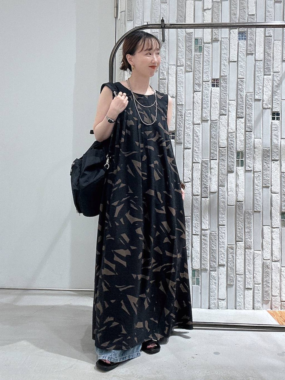 ブルー系のデニムパンツ、ブラック系のバックパック/リュック、ブラック系のサンダルを着用したレディースの夏コーディネートの2枚目の写真