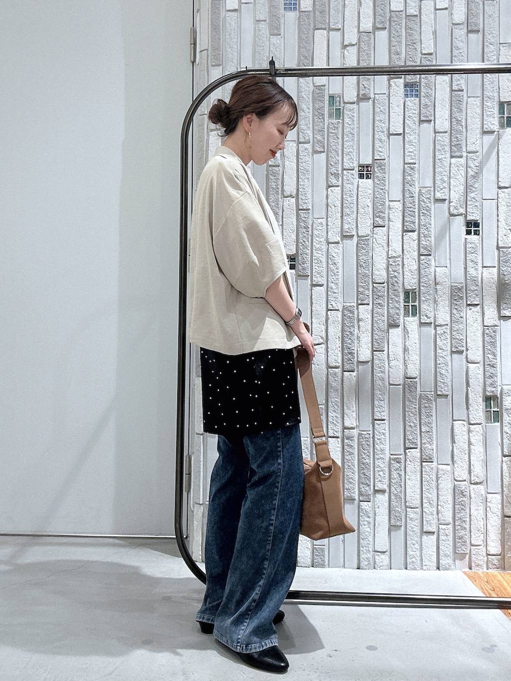 ブラウン系のショルダーバッグ、ブルー系のデニムパンツ、ベージュ系のテーラードジャケットを着用したレディースの春コーディネートの3枚目の写真