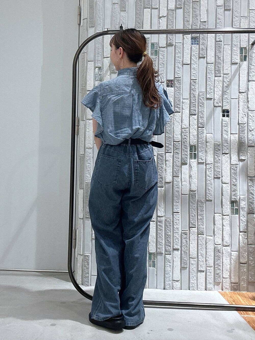 ブルー系のデニムパンツ、ブラック系のサンダル、ブラック系のショルダーバッグを着用したレディースの春コーディネートの4枚目の写真