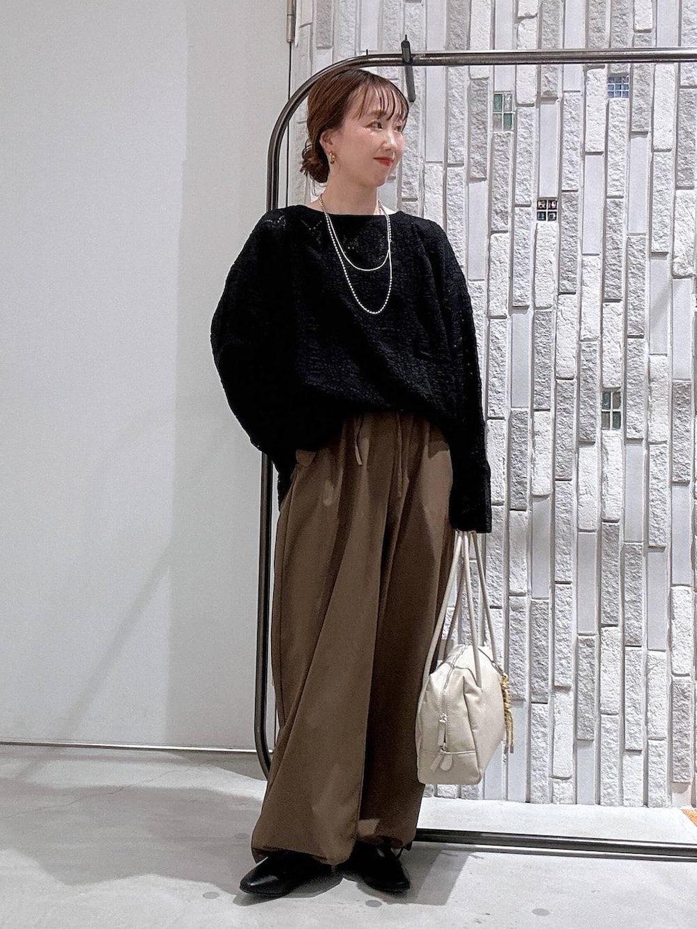 ブラウン系のその他パンツ、ホワイト系のボストンバッグ、ブラック系のTシャツ/カットソーを着用したレディースの冬コーディネートの2枚目の写真