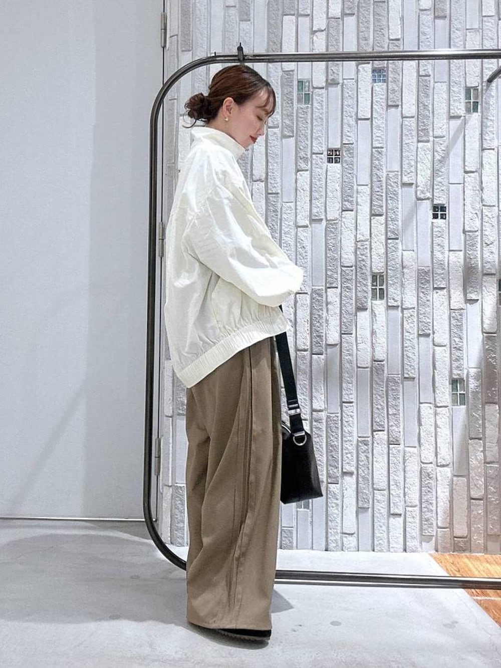 ブラック系のショルダーバッグ、ブラウン系のその他パンツ、ホワイト系のブルゾンを着用したレディースの冬コーディネートの3枚目の写真