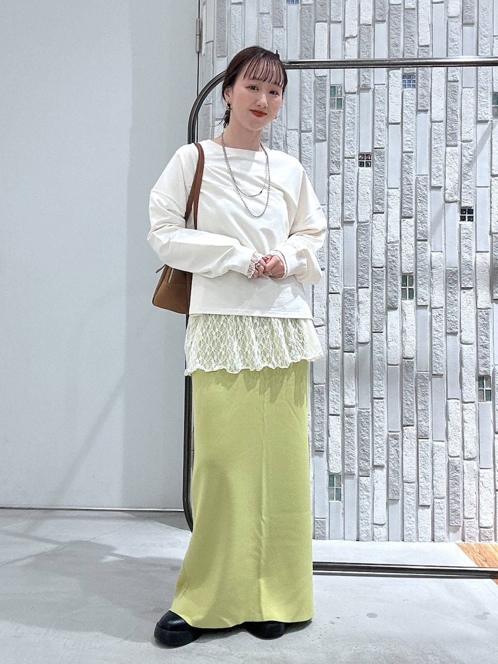 グリーン系のスカート、ブラック系のサンダル、イエロー系のボストンバッグを着用したレディースの春コーディネートの2枚目の写真