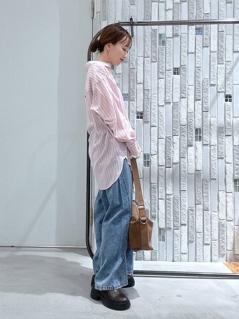 ブラウン系のショルダーバッグ、ブラウン系のサンダル、ブルー系のデニムパンツを着用したレディースの冬コーディネートの3枚目の写真