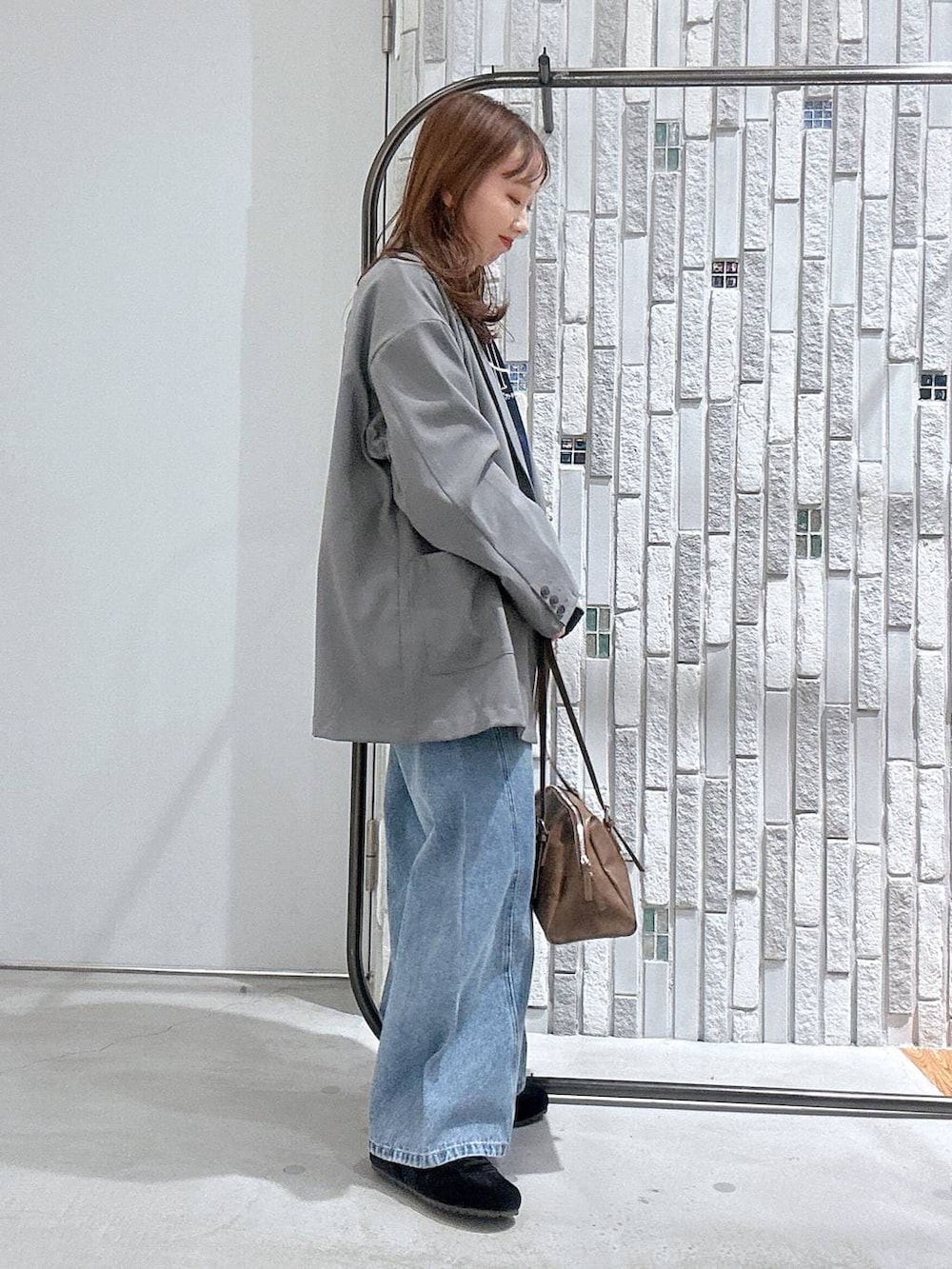 ブラウン系のボストンバッグ、ブルー系のデニムパンツ、グレー系のテーラードジャケットを着用したレディースの冬コーディネートの3枚目の写真