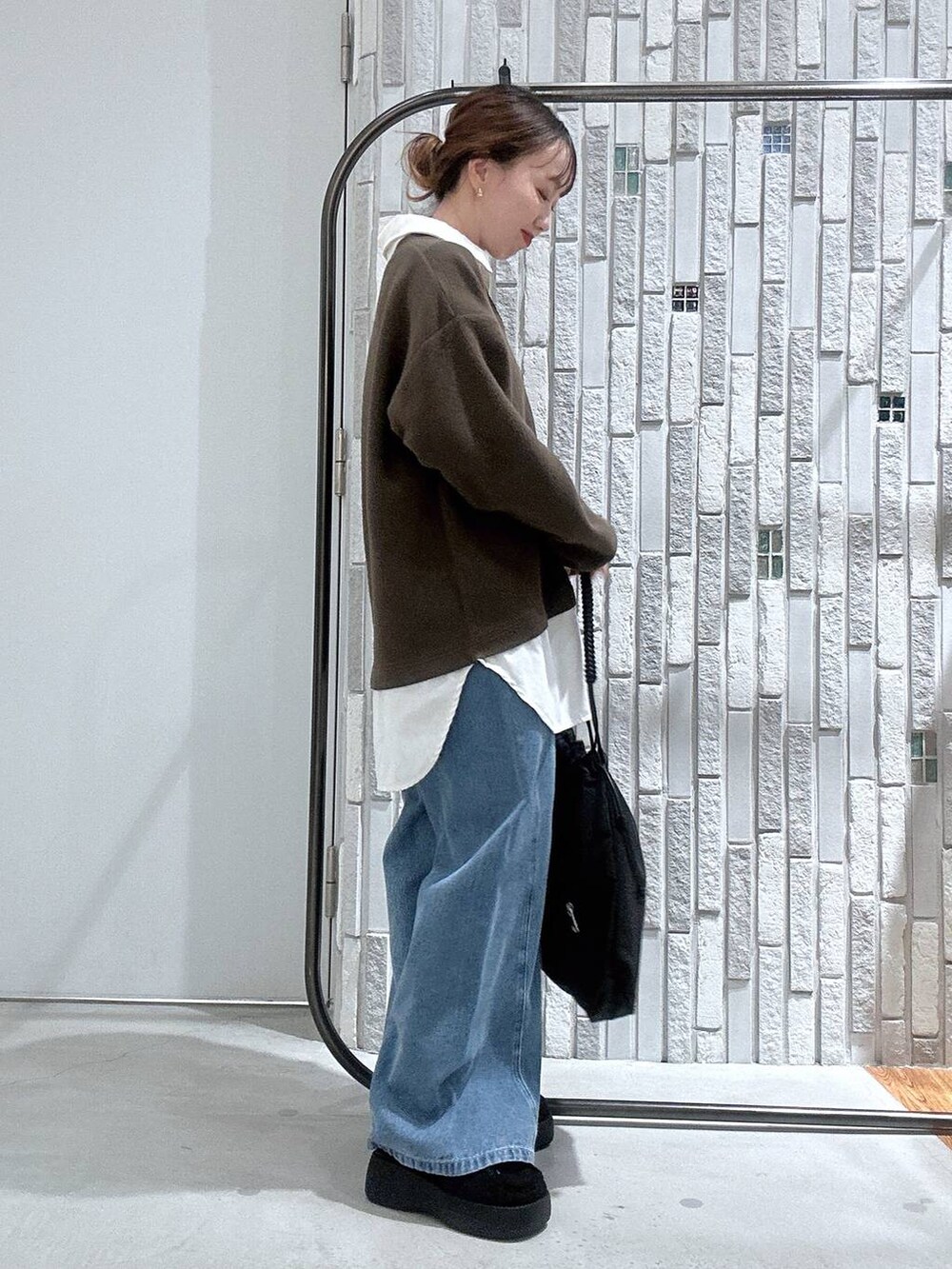 ブラック系のトートバッグ、ブルー系のデニムパンツ、ブラック系のブーツを着用したレディースの冬コーディネートの3枚目の写真