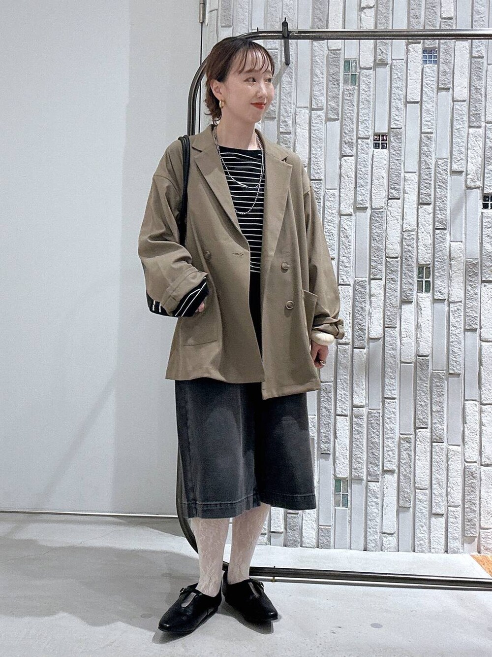 ブラウン系のテーラードジャケット、ブラック系のボストンバッグ、ブラック系のTシャツ/カットソーを着用したレディースの春コーディネートの2枚目の写真