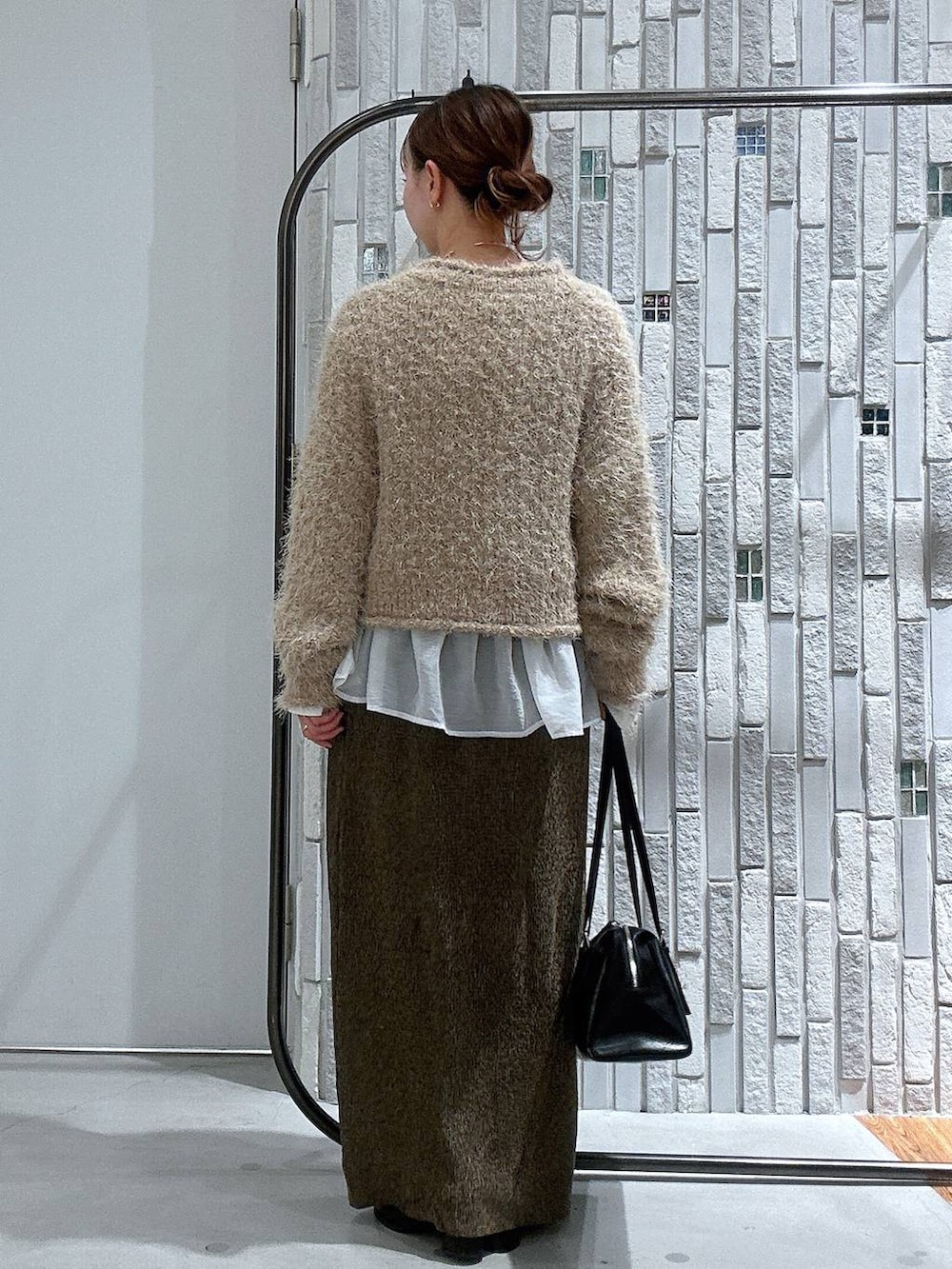 ブラック系のボストンバッグ、ホワイト系のTシャツ/カットソー、ブラック系のブーツを着用したレディースの冬コーディネートの3枚目の写真