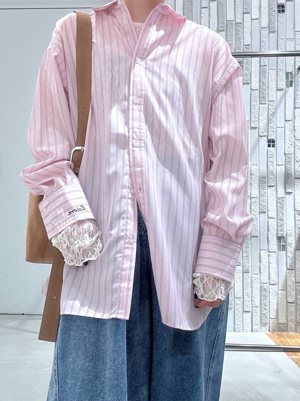 ブラウン系のショルダーバッグ、ブラウン系のサンダル、ブルー系のデニムパンツを着用したレディースの冬コーディネートの5枚目の写真