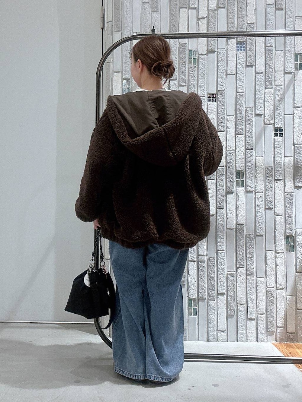 ブラック系のショルダーバッグ、ブルー系のデニムパンツ、ブラウン系のブルゾンを着用したレディースの冬コーディネートの4枚目の写真