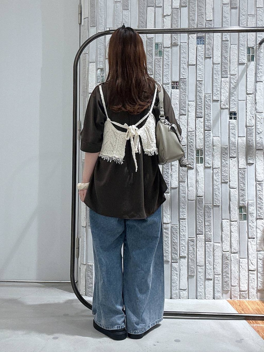 ブルー系のデニムパンツ、ブラック系のサンダル、ベージュ系のショルダーバッグを着用したレディースの春コーディネートの4枚目の写真