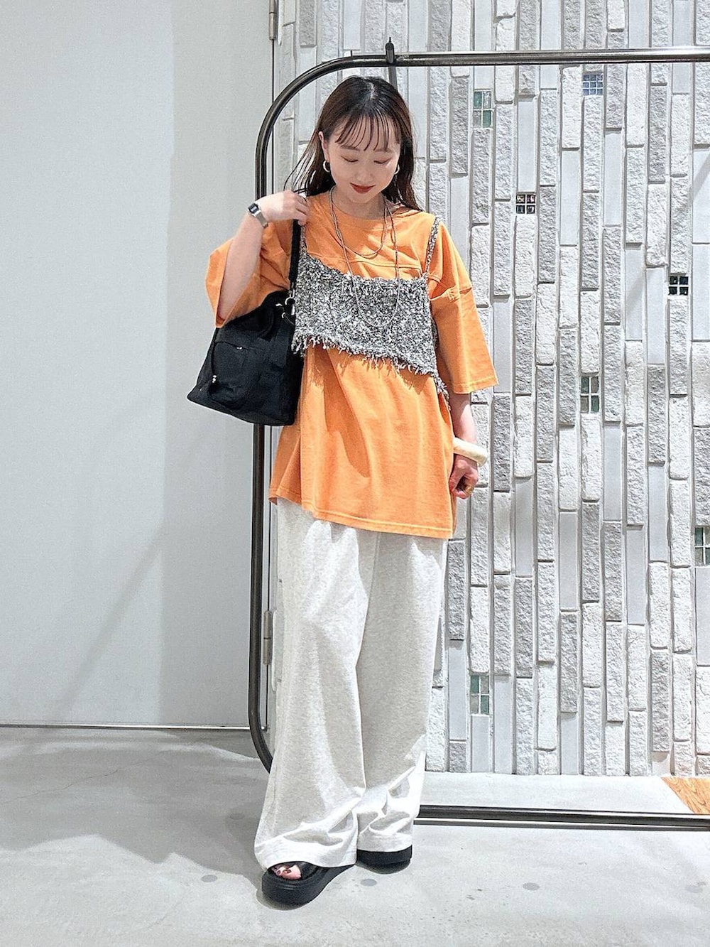 ブラック系のショルダーバッグ、ブラック系のサンダル、オレンジ系のTシャツ/カットソーを着用したレディースの春コーディネートの3枚目の写真