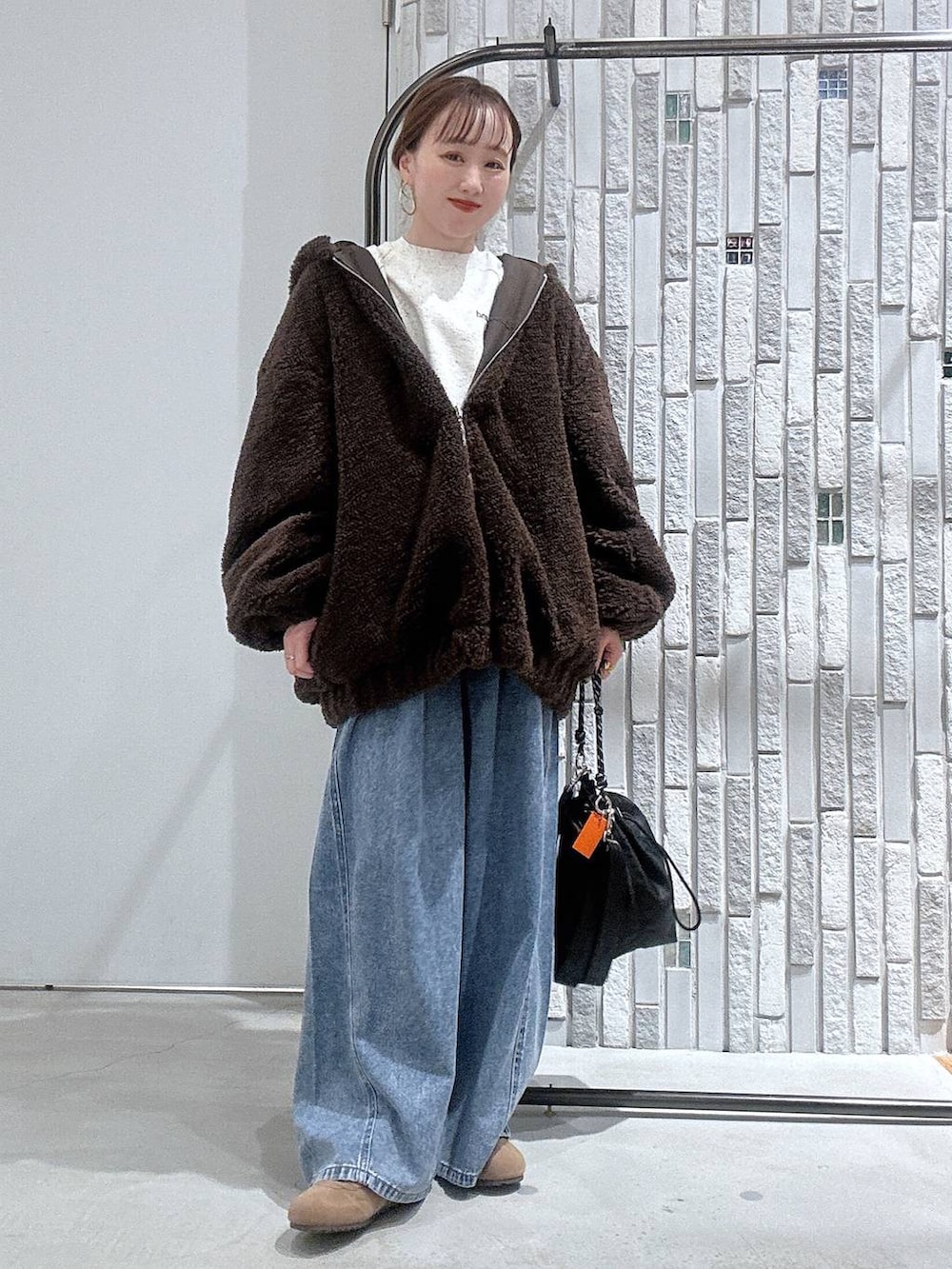 ブラック系のショルダーバッグ、ブルー系のデニムパンツ、ブラウン系のブルゾンを着用したレディースの冬コーディネートの6枚目の写真