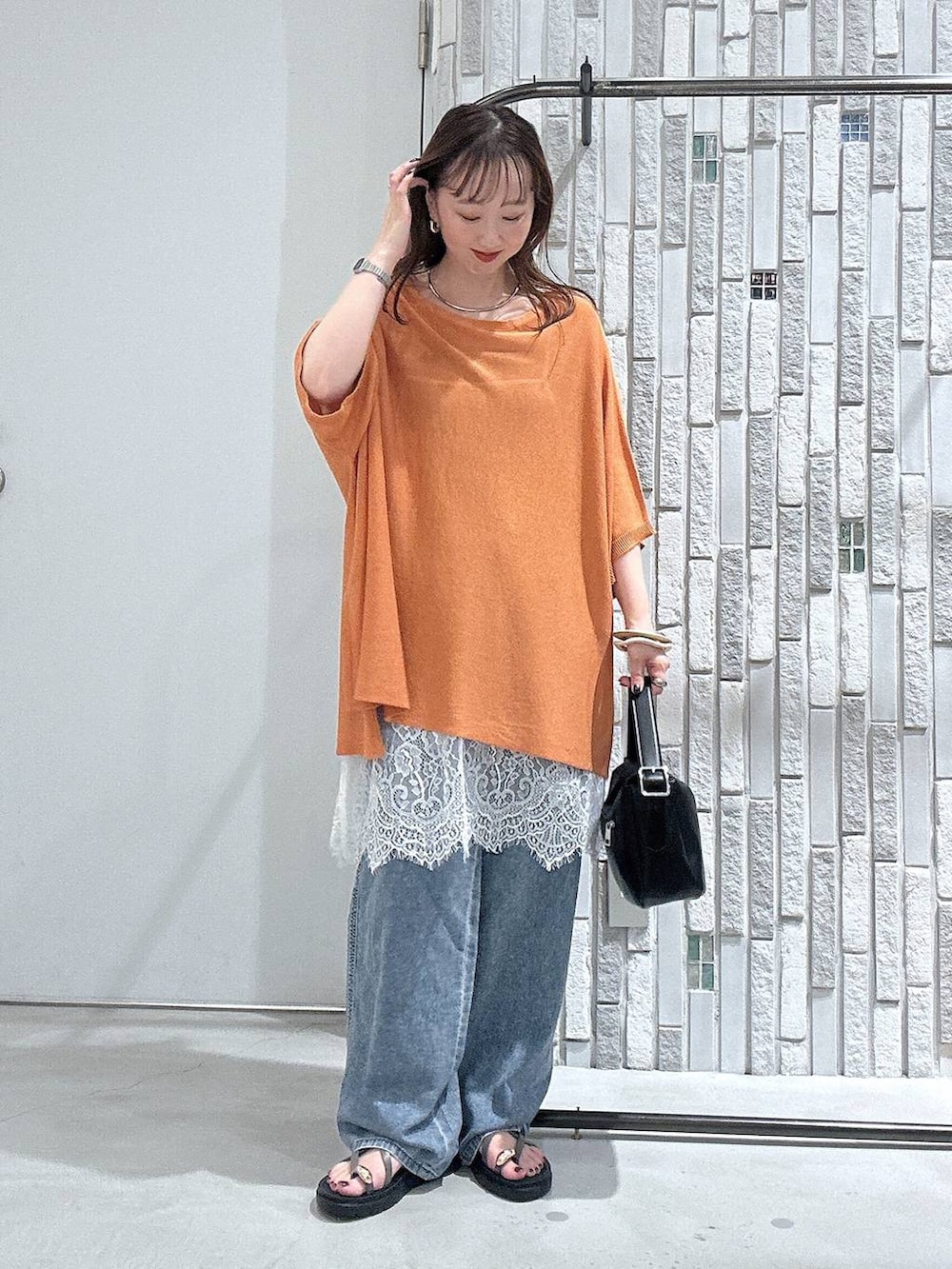 ブルー系のデニムパンツ、ブラウン系のサンダル、ブラック系のショルダーバッグを着用したレディースの夏コーディネートの2枚目の写真