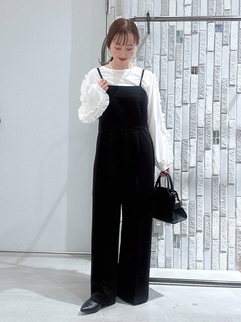 ブラック系のサロペット/オーバーオール、ホワイト系のTシャツ/カットソー、ブラック系のショルダーバッグを着用したレディースの冬コーディネートの5枚目の写真