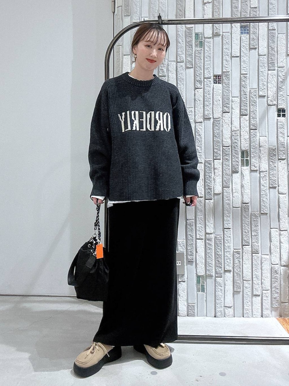 ブラック系のショルダーバッグ、ブラック系のスカート、ホワイト系のTシャツ/カットソーを着用したレディースの冬コーディネートの2枚目の写真