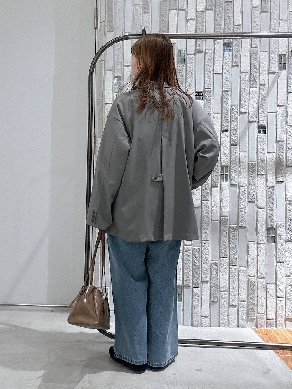 ブラウン系のボストンバッグ、ブルー系のデニムパンツ、グレー系のテーラードジャケットを着用したレディースの冬コーディネートの4枚目の写真