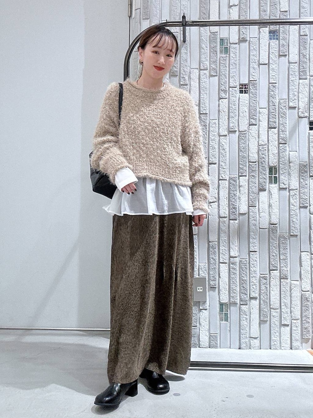 ブラック系のボストンバッグ、ホワイト系のTシャツ/カットソー、ブラック系のブーツを着用したレディースの冬コーディネートの2枚目の写真