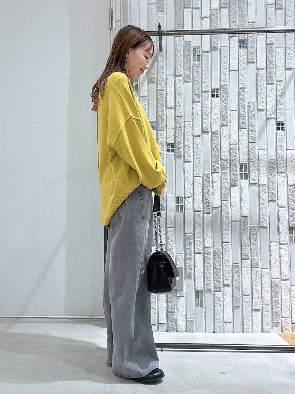 イエロー系のニット/セーター、ブラック系のブーツ、ブラック系のショルダーバッグを着用したレディースの冬コーディネートの3枚目の写真