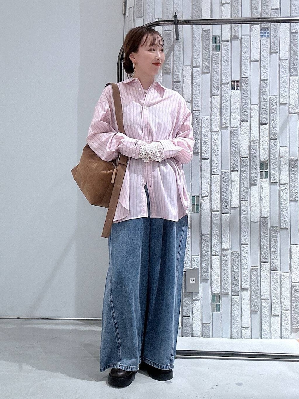 ブラウン系のショルダーバッグ、ブラウン系のサンダル、ブルー系のデニムパンツを着用したレディースの冬コーディネートの2枚目の写真